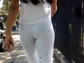 a girl and her ass in white leggings walks around the city